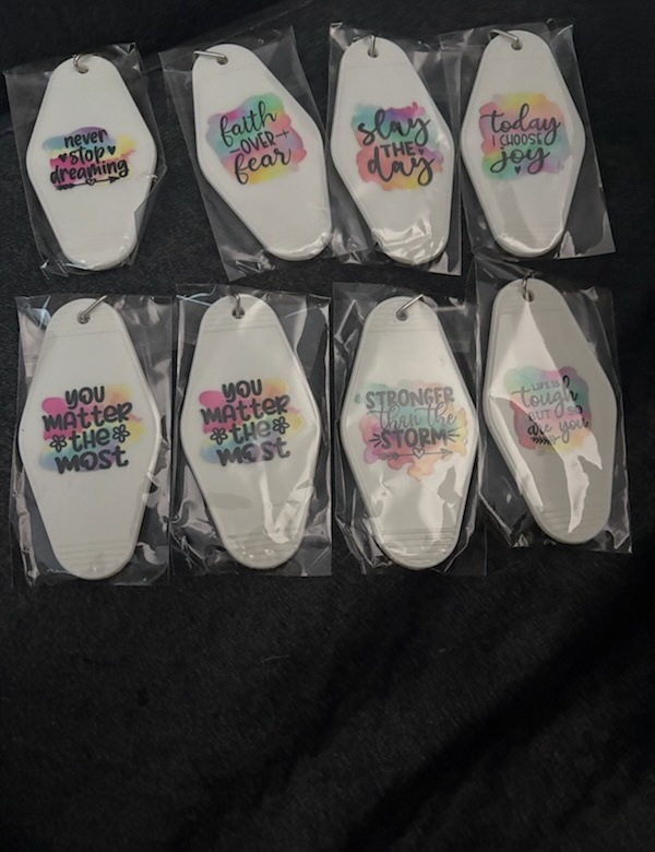 Eight handmade key chain tags with watercolor backgrounds and sayings like never stop dreaming and faith over fear